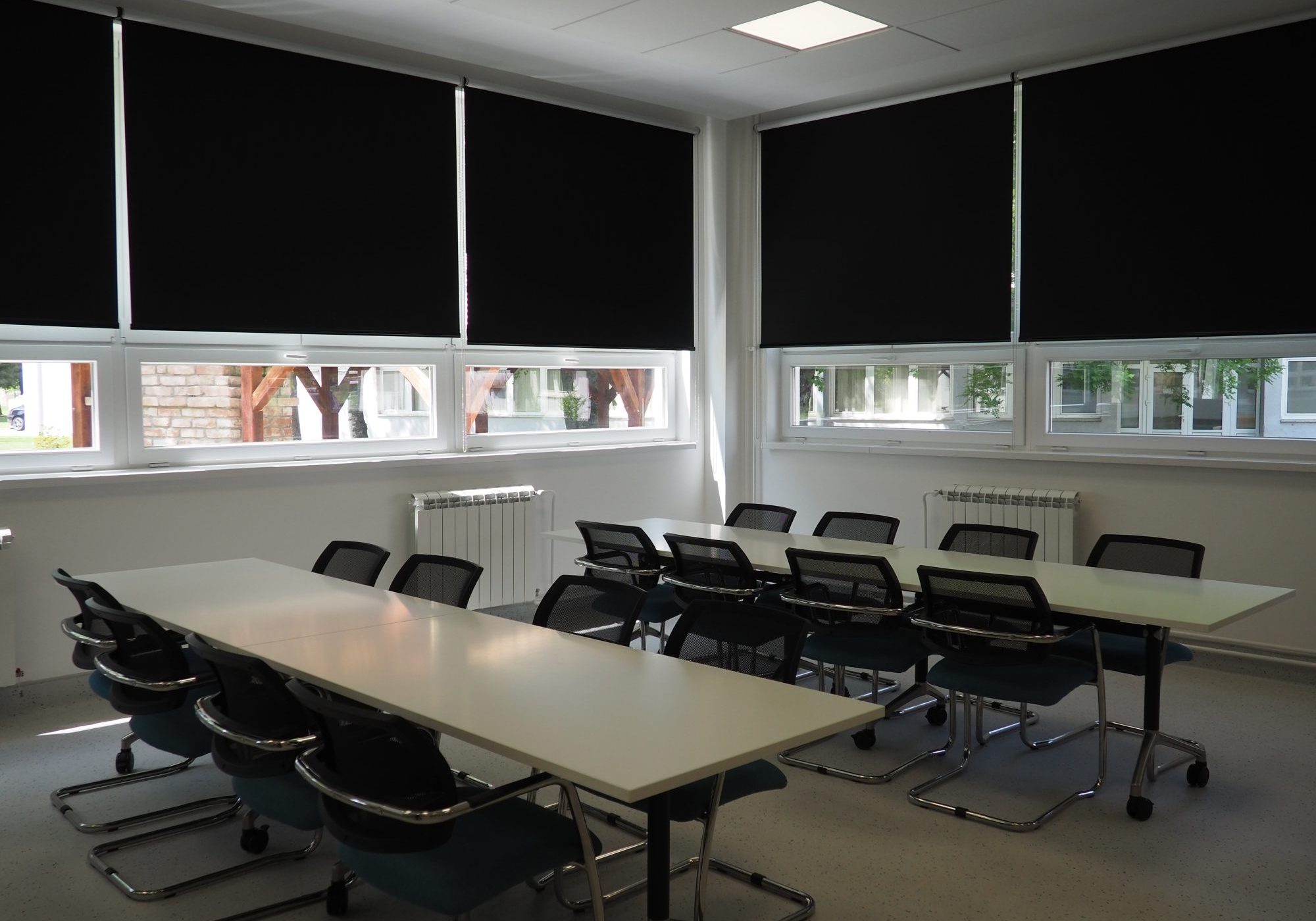 table and chairs in the meeting room in the office, in the classroom or in the library hall. White, black and gray paints in the interior. Black blinds for darkening the room. Modern interior design.